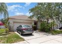 Inviting single-Gathering home with a two-car garage, featuring well-kept landscaping and mature trees at 7603 Wood Violet Dr, Gibsonton, FL 33534
