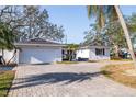 Lovely home featuring a white brick facade, two car garage, and paved driveway, nestled among mature trees at 8296 33Rd N Ave, St Petersburg, FL 33710
