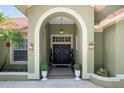 Elegant double front doors framed by an arched entryway, complemented by potted plants and sconce lighting at 9075 Waterash N Ln, Pinellas Park, FL 33782