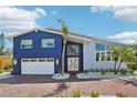 Charming two-story home with a brick driveway, well-manicured landscaping, and a white two car garage at 931 Gulf Blvd, Belleair Beach, FL 33786