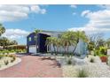 Inviting two-story home with manicured landscaping, brick driveway, and palm trees, creating an appealing curb appeal at 931 Gulf Blvd, Belleair Beach, FL 33786
