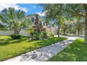 Inviting two-story home with lush lawn, garden beds, and a stone-accented facade at 10833 Breaking Rocks Dr, Tampa, FL 33647