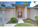Inviting front entrance with brick pillars, a covered porch, and a glass-paneled red front door at 1210 Wolford Dr, Trinity, FL 34655