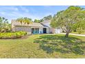 Inviting single-Gathering home with a lush lawn, palm trees, and a cozy front porch at 12222 Meadowbrook Ln, Hudson, FL 34667