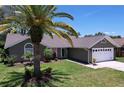 Inviting single-story home showcasing lush landscaping and a convenient two-car garage at 1445 Stonehenge Way, Palm Harbor, FL 34683