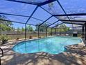 Enclosed swimming pool with a screened enclosure, patio area, and privacy fence at 1445 Stonehenge Way, Palm Harbor, FL 34683