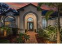 Charming home exterior with a well-manicured lawn, elegant entryway, and lush tropical landscaping at 15934 Sorawater Dr, Lithia, FL 33547
