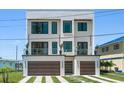 Contemporary home featuring a two-car garage, balcony, and artifical turf driveway at 16047 Redington Dr, Redington Beach, FL 33708