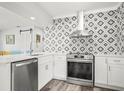 Modern kitchen with stainless steel appliances, white cabinets, and stylish backsplash at 2479 Trade Winds Dr, Dunedin, FL 34698