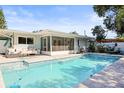 Backyard featuring a sparkling pool, covered patio, and ample seating for outdoor relaxation at 2479 Trade Winds Dr, Dunedin, FL 34698
