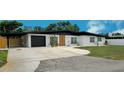 Well-maintained single-story home featuring a black roof and a spacious driveway leading to a garage at 323 48Th Nw St, Bradenton, FL 34209