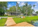 Rear exterior view featuring a large screened in lanai, waterfront access, and wooden dock at 3366 Clover Leaf Ln, Land O Lakes, FL 34639
