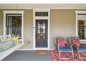 Close up of a charming front door with a wreath, rocking chairs, and a porch swing, offering a relaxing outdoor space at 4913 N Central Ave, Tampa, FL 33603