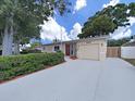 Charming single story home featuring a red entry door, manicured landscaping, and an attached garage at 6067 43Rd N Ter, Kenneth City, FL 33709