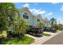 Stylish condo exterior featuring a well-maintained lawn, shrubs, and mature palm trees at 616 Garland Cir, Indian Rocks Beach, FL 33785