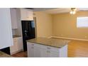 Bright kitchen with island open to the living room, showcasing granite countertops and black appliances at 6434 Old Main St, New Port Richey, FL 34653