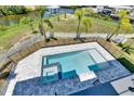 Aerial view of a sparkling pool and hot tub featuring a gray stone surround and white fencing at 6522 Simone Shores Cir, Apollo Beach, FL 33572