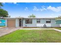 A single-story blue home with an attached garage, complemented by a green lawn and a walkway to the front door at 660 11Th N Ave, Safety Harbor, FL 34695