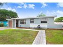 An eye-level view of a single-story home, showcasing its blue exterior, a well-kept lawn, and a quaint, paved walkway at 660 11Th N Ave, Safety Harbor, FL 34695