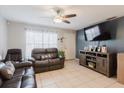 Comfortable living room features a ceiling fan, tile floors, leather furniture, and modern entertainment center at 8517 N Branch Ave, Tampa, FL 33604