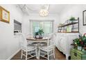 Open dining room featuring a vintage chandelier, hardwood floors, and stylish white furnishings at 10410 Ventura Ave, Tampa, FL 33619