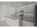 Modern kitchen featuring gray cabinets, stainless steel appliances, and a granite island at 12697 Achasta Blvd, Hudson, FL 34669