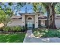 Charming home exterior featuring a light blue front door, manicured landscaping, and a large shade tree at 1905 Horseshoe Dr, Plant City, FL 33566