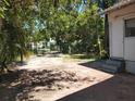 Spacious backyard area with a mix of concrete, sparse grass, mature trees and partial fencing at 1924 30Th S St, St Petersburg, FL 33712