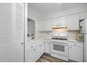 This galley kitchen features white appliances, cabinets, and wood-look flooring at 2928 Feather Dr, Clearwater, FL 33759