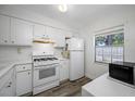 Bright kitchen features white cabinets, appliances, wood-look flooring, and window at 2928 Feather Dr, Clearwater, FL 33759