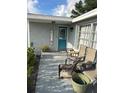 Inviting front porch with chairs, a welcome sign, and potted plants, creating a cozy and welcoming entrance to the home at 3612 Devonshire Dr, Holiday, FL 34691