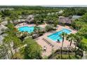 Aerial view of community pool area featuring lounge chairs, tables, and lush landscaping at 4916 Rolling Green Dr, Wesley Chapel, FL 33543