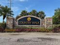 Stone community sign for Country Walk with colorful flowers and landscaping at 4916 Rolling Green Dr, Wesley Chapel, FL 33543