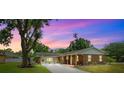 Charming single-story brick home with a long driveway, mature landscaping, and a covered front porch at twilight at 509 Falmouth St, Temple Terrace, FL 33617