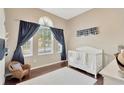 Cozy bedroom featuring a crib, a wicker chair, with hardwood floors and bright natural light from the windows at 7822 Atwood Dr, Wesley Chapel, FL 33545