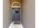 A welcoming front door featuring a decorative wreath and arched window above the gray-painted entrance at 7822 Atwood Dr, Wesley Chapel, FL 33545