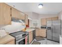 Open kitchen with stainless steel appliances, wood cabinets, and tile floors at 9466 Forest Hills Cir, Tampa, FL 33612