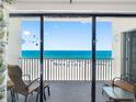 Condo balcony featuring chairs and a table with a view of the white sand beach and blue ocean at 13500 Gulf Blvd # 506, Madeira Beach, FL 33708