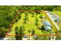 Aerial view of a large, expansive lot with mature trees, a home, shed, and ample space outlined in red at 14318 Guava St, Hudson, FL 34667