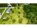 Drone shot displaying a spacious lot featuring scattered trees, a single-story home, shed, and a lush green lawn at 14318 Guava St, Hudson, FL 34667