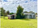 Backyard with a shed, trees, and lush green grass, under a partly cloudy sky at 14318 Guava St, Hudson, FL 34667