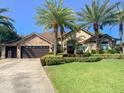 Beautiful home exterior with lush lawn, mature palms, stone accents, and three-car garage at 2041 Gold Dust Ct, Trinity, FL 34655