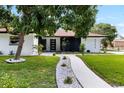 Charming home featuring a walkway lined with white stones, lush green lawn, and mature landscaping at 2306 S San Jose Cir, Tampa, FL 33629