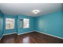 Charming bedroom featuring laminated wood floors, and ample natural light from two windows at 37712 Aaralyn Rd, Zephyrhills, FL 33542
