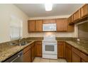 Functional kitchen featuring wooden cabinetry, granite countertops, and a complete set of appliances at 37712 Aaralyn Rd, Zephyrhills, FL 33542