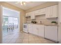 Well-lit kitchen featuring white cabinetry and tile flooring, with a breakfast area viewable through an opening at 6702 49Th N Ave, St Petersburg, FL 33709