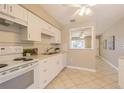 Functional kitchen with white appliances and cabinetry, complemented by tile flooring and ample counter space at 6702 49Th N Ave, St Petersburg, FL 33709