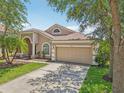 Home featuring a two-car garage, lush landscaping, and a well-kept driveway at 8124 Brinegar Cir, Tampa, FL 33647