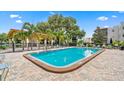 Community swimming pool with brick paver surround, metal fence, and nearby clubhouse and lounge chairs at 8174 Terrace Garden N Dr # 204, St Petersburg, FL 33709