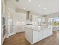Modern kitchen featuring white cabinets, a central island, and stainless steel appliances at 10320 Longmeadow Ave, Parrish, FL 34219